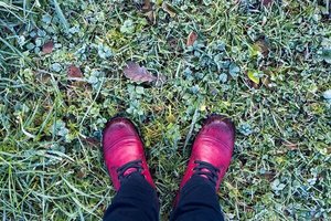 Füße mit roten Schuhen stehen am Waldboden